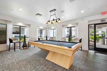 a pool table in a game room with chairs and a bar